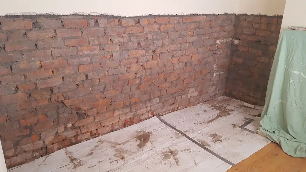 Lower wall stripped back to brick for damp proofing treatment
