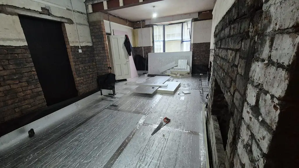 Foil-faced insulation being fitted across the floor, with cut boards and tools still in place.