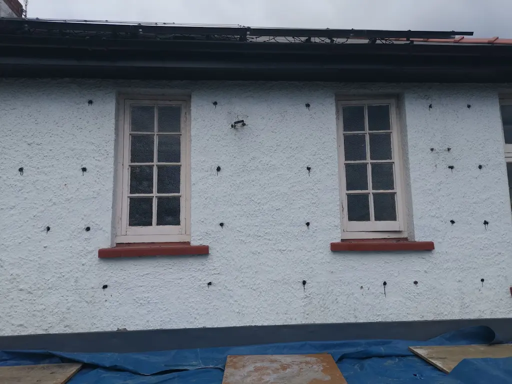 Rendered wall drilled for cavity wall-tie replacement around upper windows